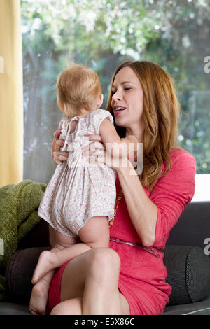 Mitte Erwachsene Frau hält Baby Tochter auf sofa Stockfoto