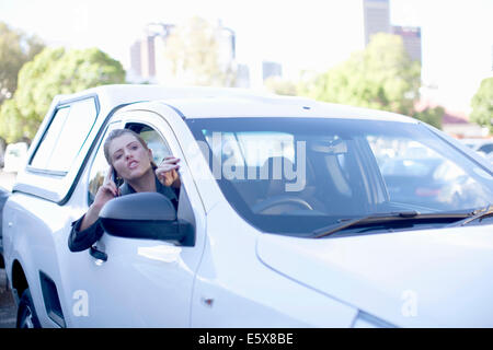 Junge Geschäftsfrau schreien aus Autofenster in Stadt Stockfoto