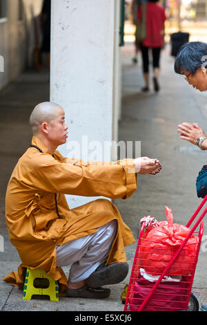 Chinesische Frau und ein junger buddhistischer Mönch auf Chun Yeung Street, Hong Kong. Stockfoto