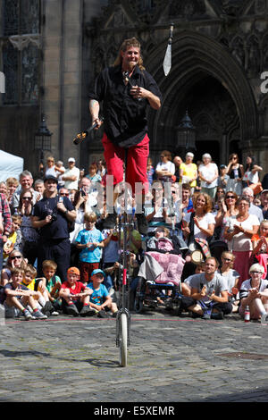 West Parliament Square, Edinburgh, Schottland, Großbritannien, Donnerstag, 7. August 2014. Street Performer Mullet man aus Neuseeland unterhalten ein Publikum mit Jonglieren auf einem Uni-Zyklus während des Edinburgh Festival Fringe neben St. Giles Cathedral Stockfoto