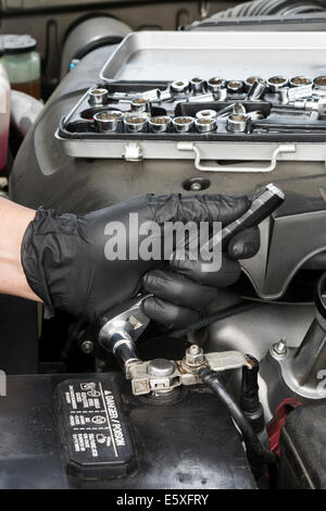 Ein Mechaniker strafft ein terminal Batteriekabel zu einem Blei Akku Beitrag. Stockfoto