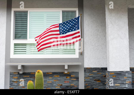Amerikanische Flagge weht im Wind beim hängen an einem Wohnhaus symbolisiert ein patriotischer Feiertag in den Vereinigten Staaten. Stockfoto