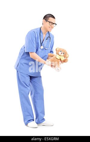 In voller Länge Portrait von einem jungen männlichen Arzt geben einen Teddybär Stockfoto