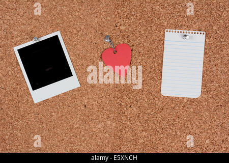 Eine Pinnwand Kork mit einem leeren Foto, ein Papierherz und leeres Blatt Papier aufgehalten mit Push-Pins. Querformat. Stockfoto