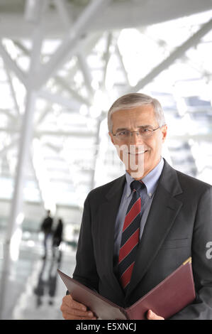Nahaufnahme eines ausgereiften Geschäftsmann in ein modernes Bürogebäude. Der Mann hält eine Leder-Portfolio und lächelnd in die camer Stockfoto