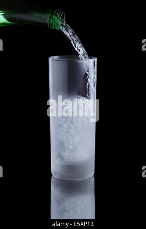 Gießen Mineralwasser, Glas, schwarzer Hintergrund Stockfoto