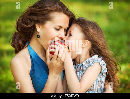 Mutter und Kind genießen den Vorfrühling, Essen Apfel, glücklich. Stockfoto