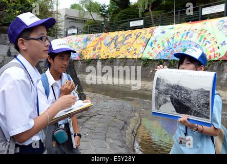 Nagasaki, Japan. 8. August 2014. Ein Schüler zeigt ein Bild der Szene nach der Atombombe in Nagasaki, 8. August 2014. Dieses Jahr markiert den 69. Jahrestag der atomaren Bomben auf Hiroshima und Nagasaki, bzw. am 6. Aug. USA und 9, 1945. Bildnachweis: Ma Ping/Xinhua/Alamy Live-Nachrichten Stockfoto