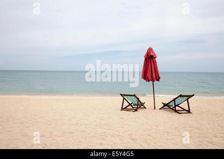 Liegestühle und einen Sonnenschirm an einem leeren Strand in Thailand Stockfoto