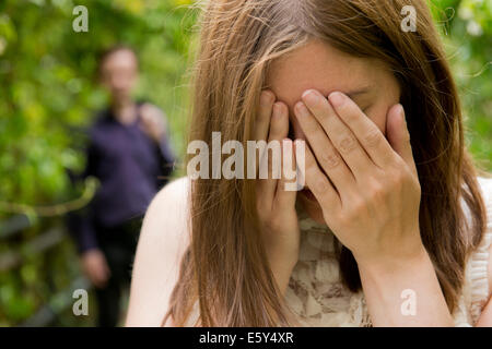 Tränenreiche Frau mit Hand auf ihr Gesicht und ihren Mann im Hintergrund. Stockfoto