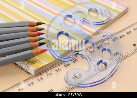 Pädagogische Ausstattung für Notebook, Buntstifte, Lineal und geometrischen Formen Schablone auf einem Desktop. England Großbritannien Großbritannien Stockfoto