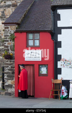 Frau in traditioneller Kleidung vor dem kleinsten Haus in Wales, in Conwy in Nordwales.