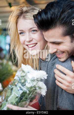 Junge Frau zufrieden nach Erhalt Blumenstrauß von Freund Stockfoto