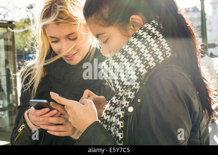 Junge Frauen zusammen ihre individuelle Smartphones betrachten Stockfoto