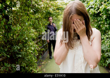 Tränenreiche Frau mit Hand auf ihr Gesicht und ihren Mann im Hintergrund. Stockfoto