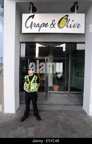 Swansea, Wales, Großbritannien. 8. August 2014. Im Bild: Polizei Aktivität am Eingang der Traube und Restaurant Olive in den Meridian Quay, Swansea, Südwales. Freitag, 8. August 2014 Re: South Wales Police kann bestätigen, dass eine Geiselnahme in der achtundzwanzigsten Etage des Turmes Meridian in Swansea Marina hat endete friedlich ohne ernsthafte Verletzungen. Offiziere hießen die Gebäude am 16:00 am Freitag, 8. August, nachdem ein Mann als Geisel in einem öffentlichen Bereich des Gebäudes, von einem anderen Mann genommen wurde, der im Besitz einer Feuerwaffe war. Bildnachweis: D Legakis/Alamy Live-Nachrichten Stockfoto