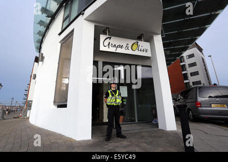 Swansea, Wales, Großbritannien. 8. August 2014. Im Bild: Polizei Aktivität am Eingang der Traube und Restaurant Olive in den Meridian Quay, Swansea, Südwales. Freitag, 8. August 2014 Re: South Wales Police kann bestätigen, dass eine Geiselnahme in der achtundzwanzigsten Etage des Turmes Meridian in Swansea Marina hat endete friedlich ohne ernsthafte Verletzungen. Offiziere hießen die Gebäude am 16:00 am Freitag, 8. August, nachdem ein Mann als Geisel in einem öffentlichen Bereich des Gebäudes, von einem anderen Mann genommen wurde, der im Besitz einer Feuerwaffe war. Bildnachweis: D Legakis/Alamy Live-Nachrichten Stockfoto