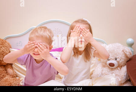 Kleinen Bruder und Schwester spielen verstecken und suchen zu Hause bedeckte Augen mit Händen, gemeinsam Spaß haben, Verwandtschaft Stockfoto