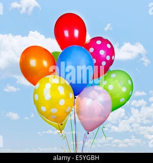 Bunte Helium-Ballons auf blauer Himmel mit Wolken Stockfoto