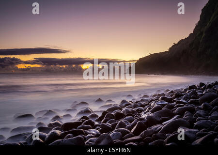 Sonnenaufgang am einsamen Strand im Waipi'o Valley, Big Island, Hawaii. Wellen an den Felsen. Stockfoto