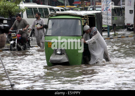 Lahore, Pakistan. 9. August 2014. Ein pakistanischer Mann schiebt seine Auto-Rikscha in einer überfluteten Straße nach schweren Monsun-Regen in östlichen Pakistan Lahore am 9. August 2014. Bildnachweis: Jamil Ahmed/Xinhua/Alamy Live-Nachrichten Stockfoto