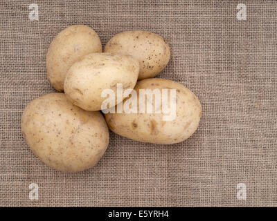 Grundnahrungsmittel. Ungekochte Kartoffeln auf rustikalen Sack, Hessische Hintergrund. Stockfoto