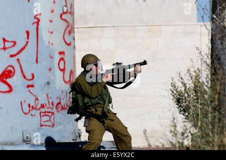 Ein israelischer Soldat bekommt ein Tränengas-Behälter bei Protesten schussbereit. Er steht vor dem berüchtigten Wachturm und militärischen Kontrollpunkt als Rachels Grab und Checkpoint 300 bekannt. Freitagnachmittag wurde Rage in der West Bank erklärt. Früh am Morgen, nach 08:00, die 72-Stunden Waffenruhe zwischen Gaza und Israel endete und kämpfen wieder aufgenommen. In den frühen Abendstunden israelischen Truppen erschossen und Ahmad Mohammad al-Katar aus al-Amari Flüchtlingslager in der Nähe von Ramallah, als Proteste weiter solidarisch für Gaza im Westjordanland getötet. Während der Proteste gab es in Hebron über 40 verletzte. MEA Stockfoto