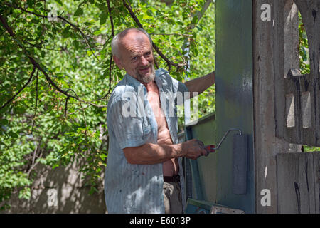 Im Alter von Haus Maler malt die vertikale Metalloberfläche mit der Walze. Stockfoto