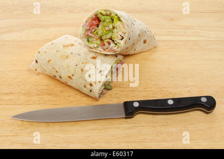 Speck-Salat Brot wickelt auf Holzbrett mit einem Messer Stockfoto