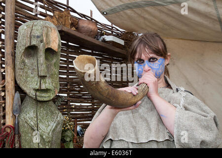 Viking Frau mit Gefärbtem Gesicht abblasen Tier Horn mit geschnitzten menschliches Gesicht, eine hölzerne Statue in Ardesier, Invernesshire, schottische Homecoming Event. Feier der Jahrhunderte am Fort George mit lebendiger Geschichte camps umreißt wichtige Perioden in die Vergangenheit der alten Schottland. Stockfoto