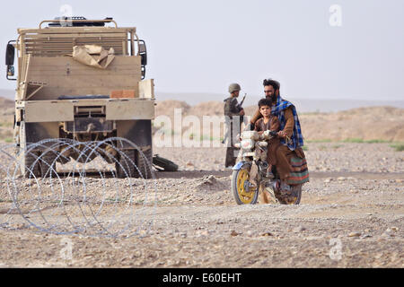 Afghanische Zivilisten fahren Sie vorbei ein Afghan National Army Soldat an einem Checkpoint Fahrzeug 14. Juli 2014 im Dorf Shekasteh Tappeh, Provinz Helmand, Afghanistan, 14. Juli 2014. Stockfoto