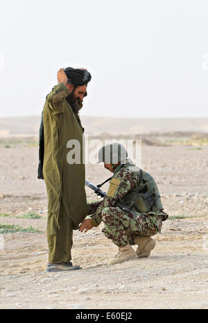 Ein Afghane wird von einem afghanischen Nationalarmee Soldaten an einem Fahrzeug Checkpoint 14. Juli 2014 im Dorf Shekasteh Tappeh, durchsucht der Provinz Helmand, Afghanistan, 14. Juli 2014. Stockfoto