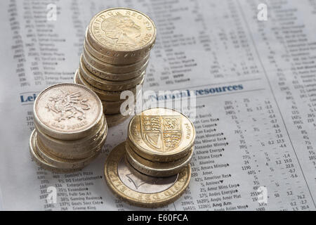 Pound Münzen auf einer Zeitung Seite anzeigen Aktienkurse gestapelt Stockfoto