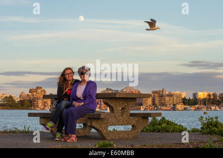 Großmutter und Enkelin posiert mit Vollmond und die Skyline der Stadt im Hintergrund-Victoria, British Columbia, Kanada. Stockfoto