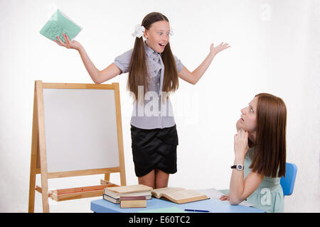 Schüler an der Tafel steht, der Lehrer sitzt an seinem Schreibtisch und hört auf den Schüler Stockfoto