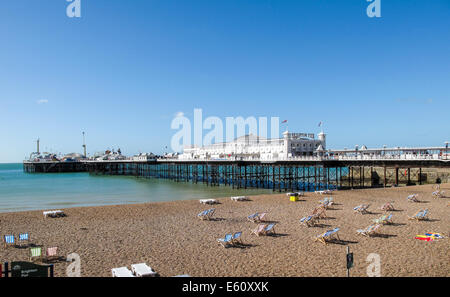 Brighton Pier und leere Liegestühle am Strand von Brighton an einem sonnigen Sommernachmittag mit einem klaren blauen Himmel Stockfoto