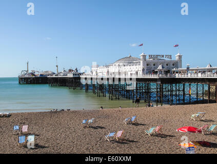 Brighton Pier und leere Liegestühle am Strand von Brighton an einem sonnigen Sommernachmittag mit einem klaren blauen Himmel Stockfoto