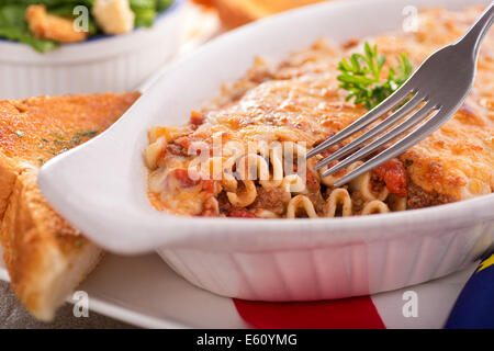 Eine frisch gebackene hausgemachte Lasagne mit Knoblauchbrot und Caesar Salat. Stockfoto