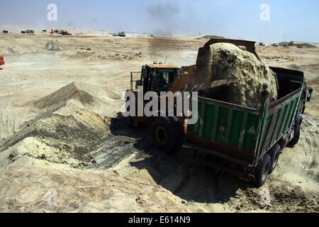 Ismailia, Ägypten. 10. August 2014. Ein ägyptischer Arbeiter trägt Sand auf der Baustelle des Projektes "Neue Suez Canal" in Ismailia Hafenstadt, nordöstlich von Kairo, Ägypten, am 10. August 2014. Ägyptens Präsident Abdel Fattah al-Sisi stellte am vergangenen Dienstag den Bau einer 72 km "neue Suez-Kanal" Verkehr neben dem bestehenden Wasserstraße, die das Rote Meer mit dem Mittelmeer verbindet beschleunigen und Ägyptens angeschlagenen Wirtschaft ankurbeln soll. © Ahmed Gomaa/Xinhua/Alamy Live-Nachrichten Stockfoto