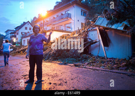 Bad Schwalbach, Deutschland. 10. August 2014. Inhaber Hedwig Grimm steht vor ihrem zerstörten Hotel "Haus am Park" in Bad Schwalbach, Deutschland, 10. August 2014. Kurz nachdem die letzten Gäste gegangen war, fielen mehrere Bäume auf dem Dach des Hotels. Ein Tornado gemeinsam mit einer regen Sturm verursachte Schäden in Millionenhöhe in den Kurort. Zahlreiche Autos wurden beschädigt, Dächer der Häuser abgenommen und Waldflächen zerstört. Foto: Boris Roessler/Dpa/Alamy Live News Stockfoto