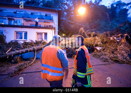 Bad Schwalbach, Deutschland. 10. August 2014. Feuerwehrleute stellen Sie sich vor ihrem zerstörten Hotel "Haus am Park" in Bad Schwalbach, Deutschland, 10. August 2014. Kurz nachdem die letzten Gäste gegangen war, fielen mehrere Bäume auf dem Dach des Hotels. Ein Tornado gemeinsam mit einer regen Sturm verursachte Schäden in Millionenhöhe in den Kurort. Zahlreiche Autos wurden beschädigt, Dächer der Häuser abgenommen und Waldflächen zerstört. Foto: Boris Roessler/Dpa/Alamy Live News Stockfoto