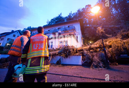 Bad Schwalbach, Deutschland. 10. August 2014. Feuerwehrleute stellen Sie sich vor ihrem zerstörten Hotel "Haus am Park" in Bad Schwalbach, Deutschland, 10. August 2014. Kurz nachdem die letzten Gäste gegangen war, fielen mehrere Bäume auf dem Dach des Hotels. Ein Tornado gemeinsam mit einer regen Sturm verursachte Schäden in Millionenhöhe in den Kurort. Zahlreiche Autos wurden beschädigt, Dächer der Häuser abgenommen und Waldflächen zerstört. Foto: Boris Roessler/Dpa/Alamy Live News Stockfoto