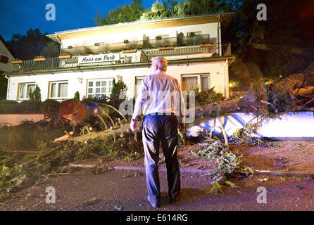 Bad Schwalbach, Deutschland. 10. August 2014. Inhaber Josef Grimm steht vor seinem zerstört teilweise Hotel "Haus am Park" in Bad Schwalbach, Deutschland, 10. August 2014. Kurz nachdem die letzten Gäste gegangen war, fielen mehrere Bäume auf dem Dach des Hotels. Ein Tornado gemeinsam mit einer regen Sturm verursachte Schäden in Millionenhöhe in den Kurort. Zahlreiche Autos wurden beschädigt, Dächer der Häuser abgenommen und Waldflächen zerstört. Foto: Boris Roessler/Dpa/Alamy Live News Stockfoto