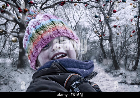 Mädchen in Winterkleidung vor Bäumen mit Weihnachtskugeln Stockfoto