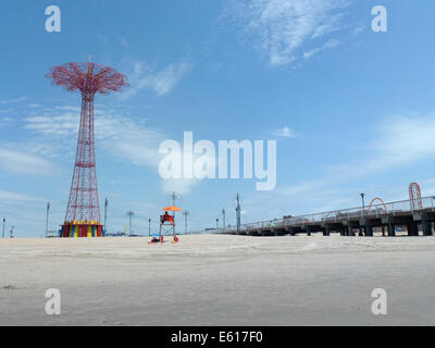 Der Fallschirm springen (L) und anderen Festplatz Fahrten stehen an der Strandpromenade von Brighton Beach auf Coney Island, New York, USA, 24. Juni 2014. Der Parachute Jump ist ein 80 Meter hohen roten Stahlturm mit einem Gewicht von 150 Tonnen. Ursprünglich es war Teil der New York World Ausstellung 1939 im Flushing Meadows Park und wurde von den Betreibern der Steeplechase Park wo es bis 1968 diente hier gebracht. Seit Juli 1977 der Turm ist eines der Wahrzeichen der Stadt und ist seit 1989 unter Denkmalschutz. Foto: Alexandra Schuler - Achtung! KEIN KABEL-SERVICE- Stockfoto