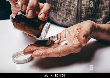 Nahaufnahme Bild senior Frau Pillen aus der Pillen-Flasche herausnehmen. Konzentrieren Sie sich auf Händen. Alte Frauen nehmen Medikamente. Stockfoto