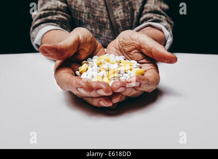 Alte Frau mit Pillen und Medizin beim Sitzen an einem Tisch. Konzentrieren Sie sich auf Hände und Pillen. Close-up erschossen senior weibliche Hände ho Stockfoto