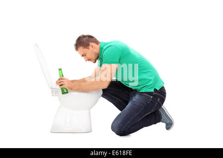Betrunkener Mann hält eine Bierflasche und stützte sich auf eine Toilette Stockfoto