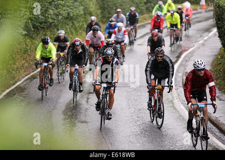 West Horsley, UK. 10. August 2014. Fahrer in den aufsichtsrechtlichen RideLondon-Surrey 100 sind durchnässt, durchschreiten West Horsley, Surrey mit dem schweren witterungsbedingt verkürzt. Bildnachweis: Oliver Dixon/Alamy Live-Nachrichten Stockfoto