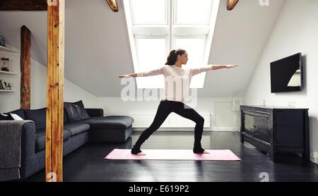 Voller Länge Bild der attraktiven jungen Frau, die Ausübung auf Matte im Wohnzimmer. Passen Sie Dame beim Yoga zu Hause. Stockfoto